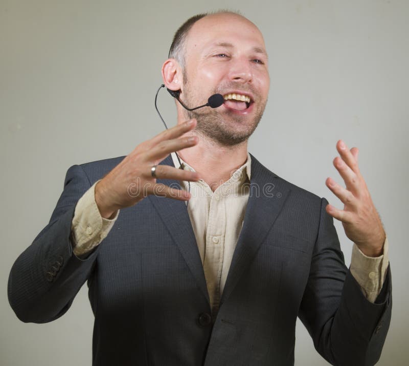 Orateur attirant et sûr heureux d'homme d'affaires avec le casque donnant la formation de entraînement de conférence pour le sour photos stock Orateur attirant et sûr heureux d'homme d'affaires avec le casque donnant la formation de entraînement de conférence pour le sour photos stock