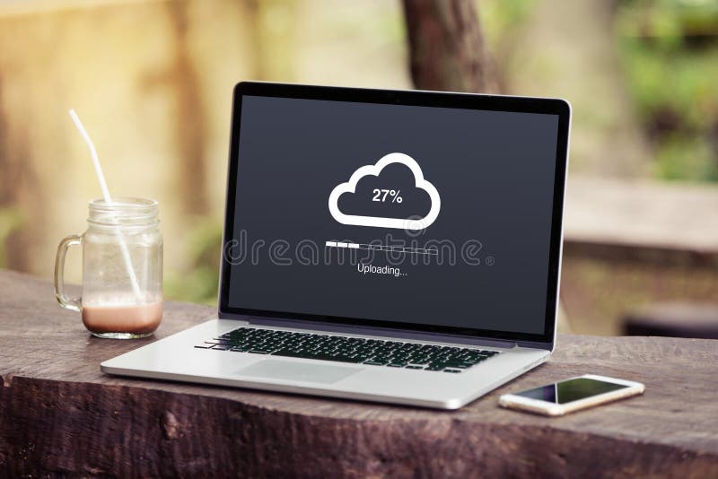 Ordenador portátil con concepto que carga de la nube en la pantalla en el parque/el jardín con la bebida del teléfono y del choco imagen de archivo libre de regalías