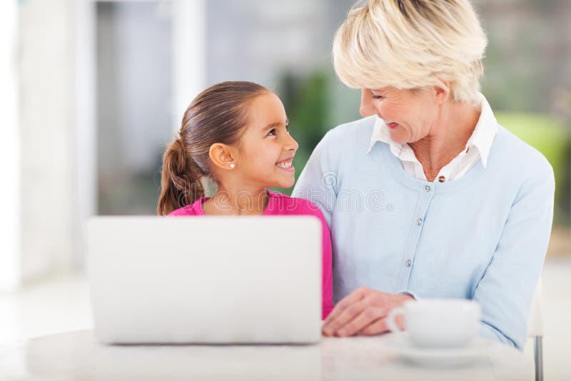 Cheerful little girl and grandma using laptop computer at home. Cheerful little girl and grandma using laptop computer at home