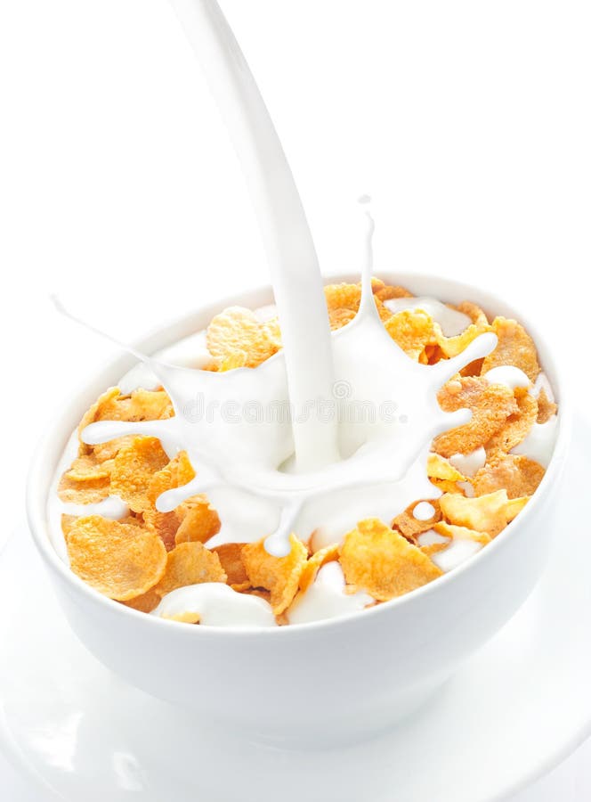 Appetizing view of milk pouring into a bowl of nutritious and delicious corn flake cereal. Appetizing view of milk pouring into a bowl of nutritious and delicious corn flake cereal