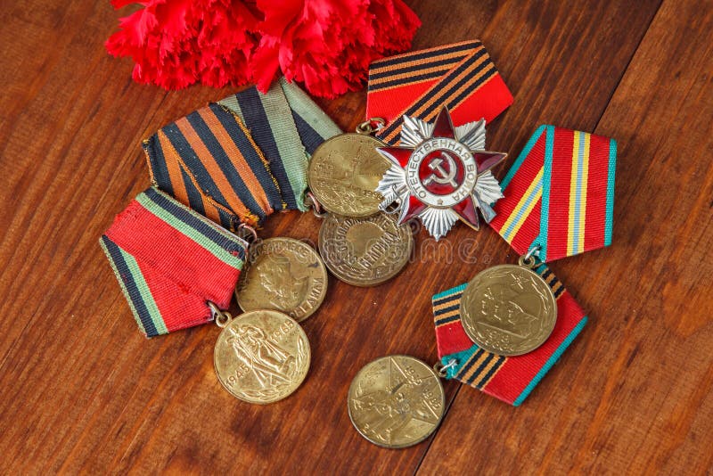 Order of the Patriotic War in St. and Medals for the victory over Germany and two red flower on a table. close up. selective focus stock image Order of the Patriotic War in St. and Medals for the victory over Germany and two red flower on a table. close up. selective focus stock image