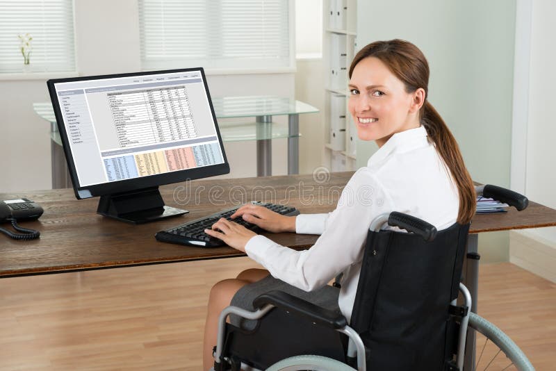 Ordinateur d'On Wheelchair Using de femme d'affaires dans le bureau photo libre de droits Ordinateur d'On Wheelchair Using de femme d'affaires dans le bureau photo libre de droits