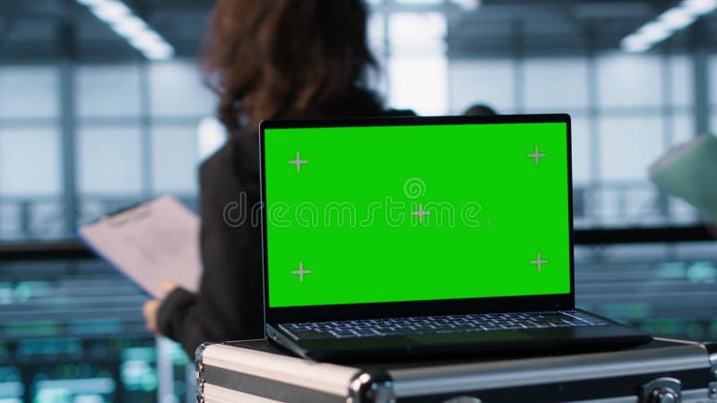 Ordinateur portable à écran vert devant les ingénieurs du datacenter inspectant les serveurs banque de vidéos