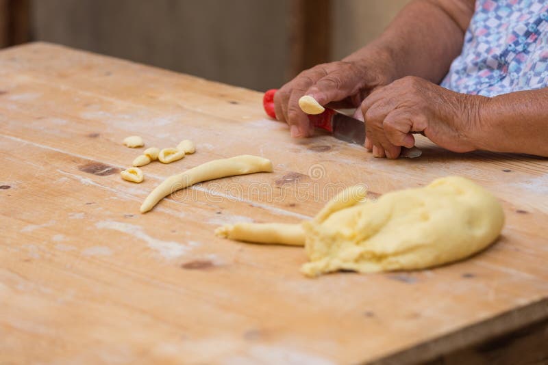 A typical orecchiette lady from the italian city Bari finishing orecchiettte with the finger. A typical orecchiette lady from the italian city Bari finishing orecchiettte with the finger