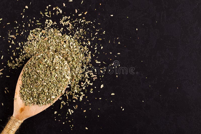 Oregano, zerkleinert in einem Holzlöffel auf einem schwarzen Tisch Konzept, Kopierraum stockbilder