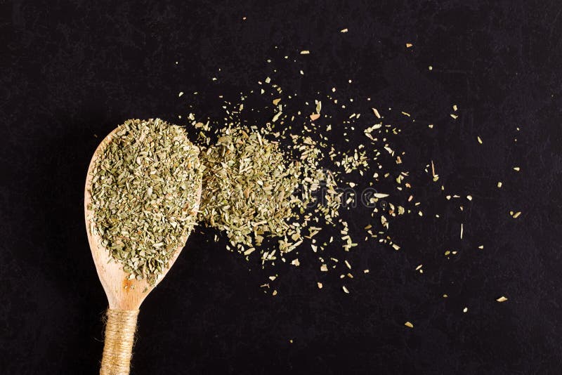 Oregano, zerkleinert in einem Holzlöffel auf einem schwarzen Tisch Konzept, Kopierraum lizenzfreie stockbilder