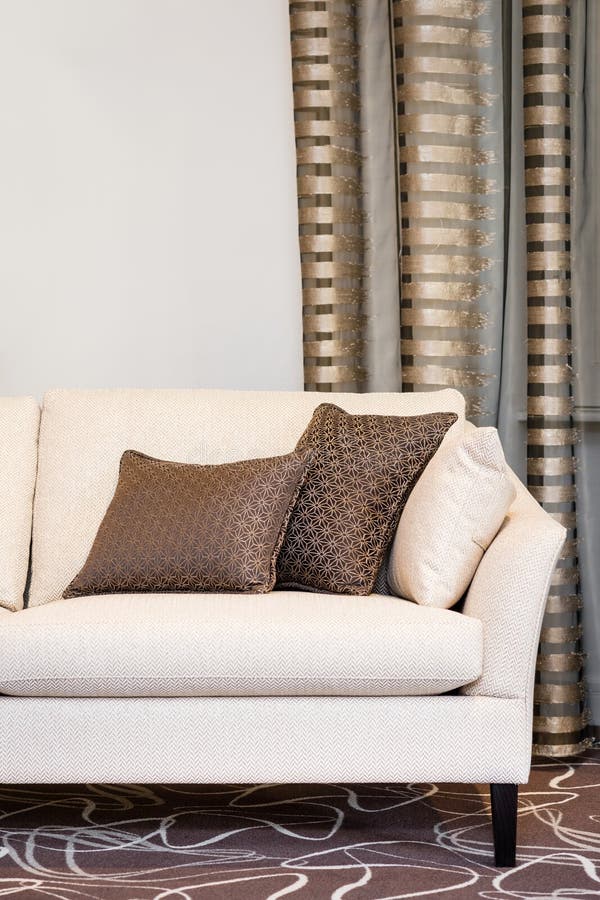 Oreillers de Brown sur le sofa beige vide photographie stock Oreillers de Brown sur le sofa beige vide photographie stock