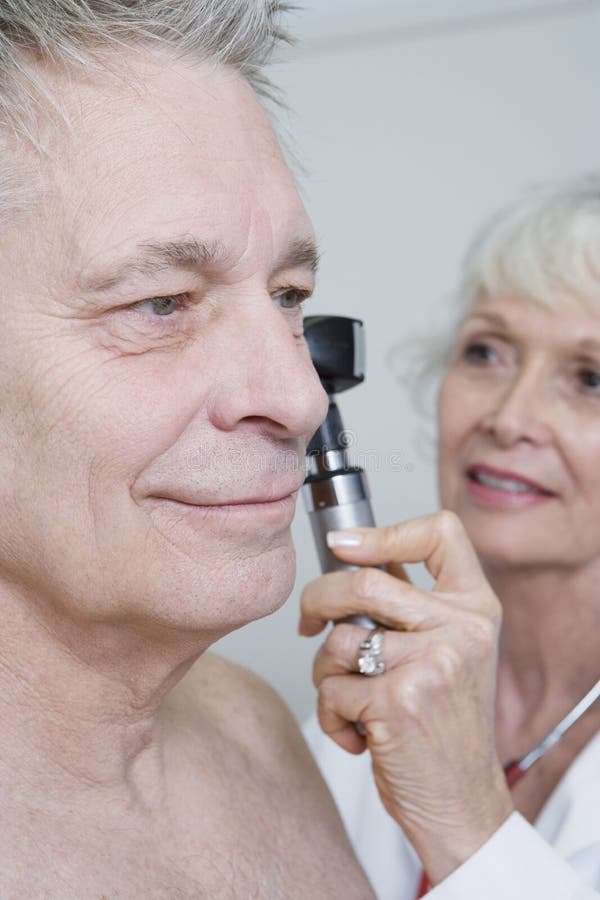 Orelha do doutor Examining Patient usando o Otoscope imagem de stock royalty free Orelha do doutor Examining Patient usando o Otoscope imagem de stock royalty free