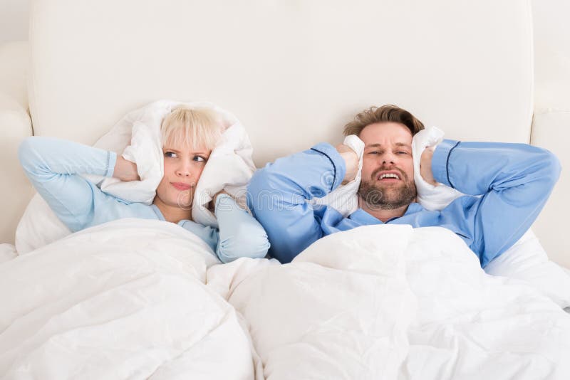 Orelhas da coberta dos pares ao dormir na cama imagens de stock royalty free Orelhas da coberta dos pares ao dormir na cama imagens de stock royalty free