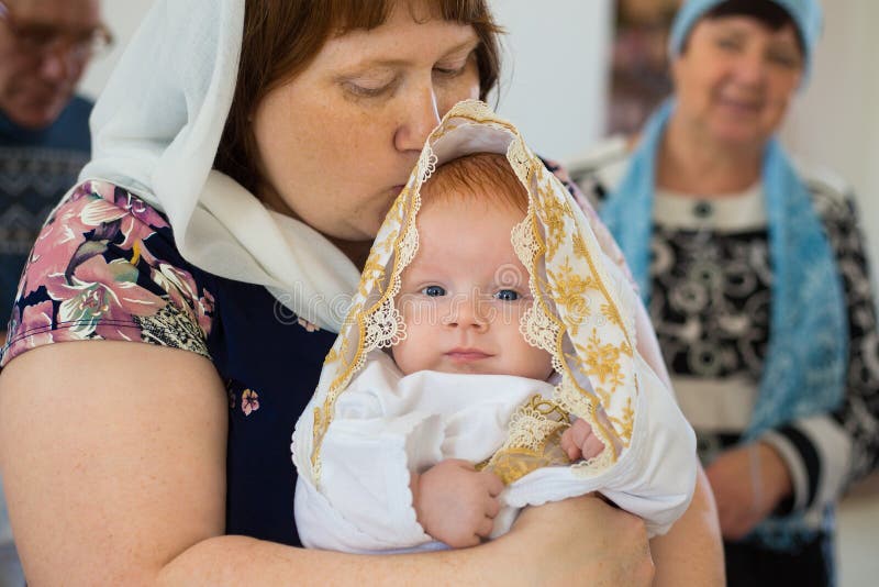 Orenburg, russo Federation-2 Aprel 2019 Mulher que guarda um bebê durante o ritual do batismo foto de stock Orenburg, russo Federation-2 Aprel 2019 Mulher que guarda um bebê durante o ritual do batismo foto de stock