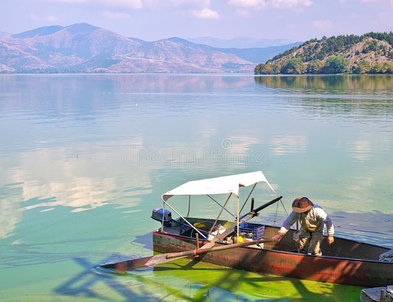 Orestiada lake, Kastoria, Greece. Fisherman in traditional wooden boat