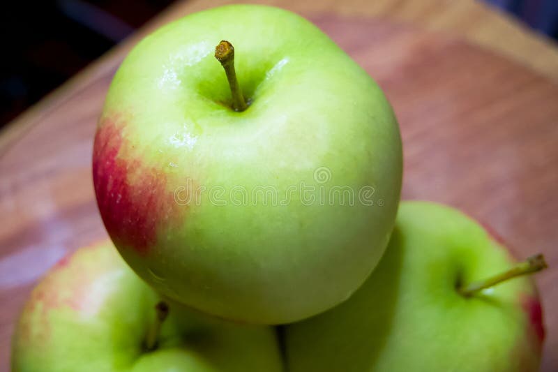 Organic Apple Display. Green apples, one in focus, on a rustic wood backdrop stock photography