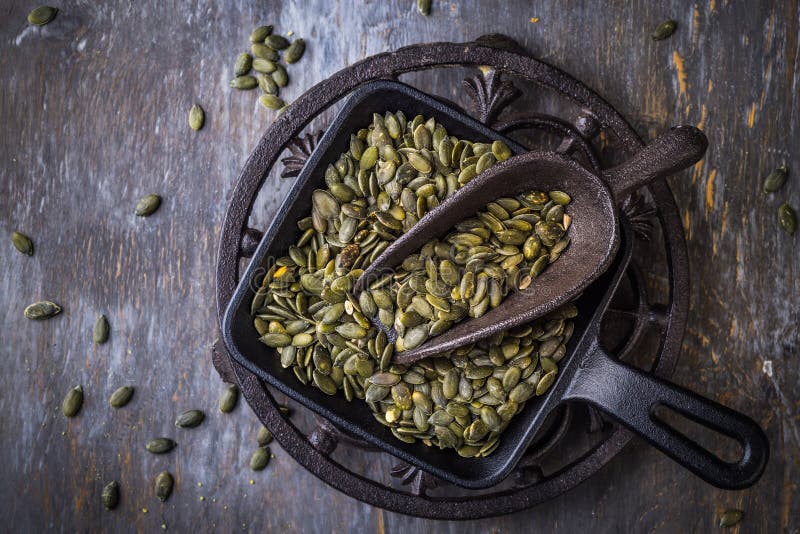 Organic pumpkin seeds with scoop in a bowl royalty free stock photos