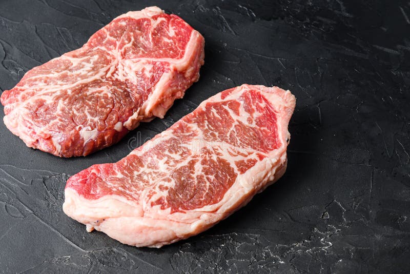 Organic Top Blade Steak Cuts, on Black Textured Background Side View