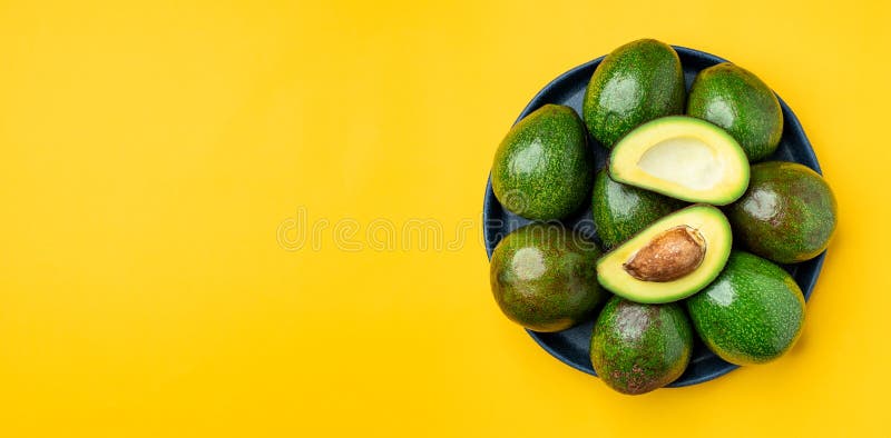 Organicznie avocados połówki cięcie z nasieniodajną i całą owoc w talerzu na koloru żółtego stołu tła odgórnym widoku Zdrowi supe obrazy royalty free Organicznie avocados połówki cięcie z nasieniodajną i całą owoc w talerzu na koloru żółtego stołu tła odgórnym widoku Zdrowi supe obrazy royalty free