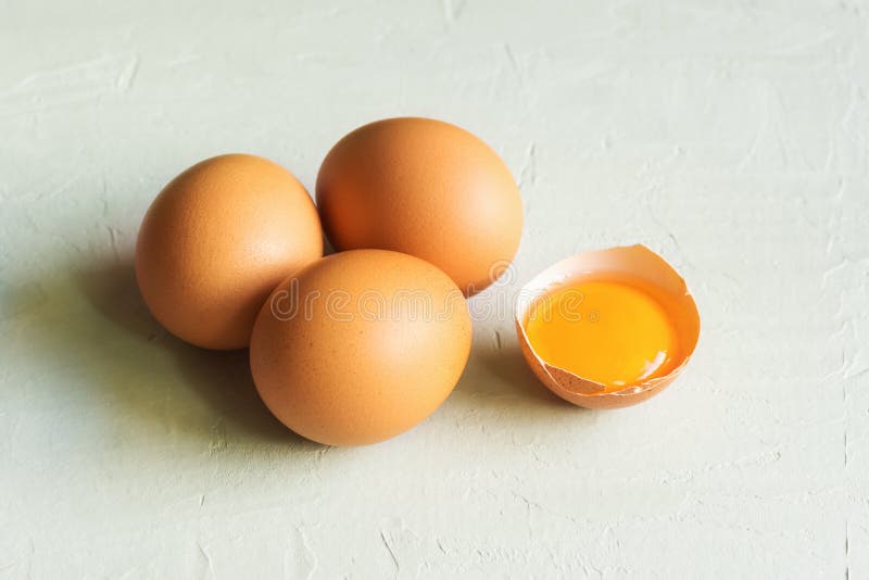Organische braune Eier des ganzen und gebrochenen Freilands mit hellem sonnigem glattem Eigelb auf grauem Steinhintergrund Kochen lizenzfreies stockbild Organische braune Eier des ganzen und gebrochenen Freilands mit hellem sonnigem glattem Eigelb auf grauem Steinhintergrund Kochen lizenzfreies stockbild