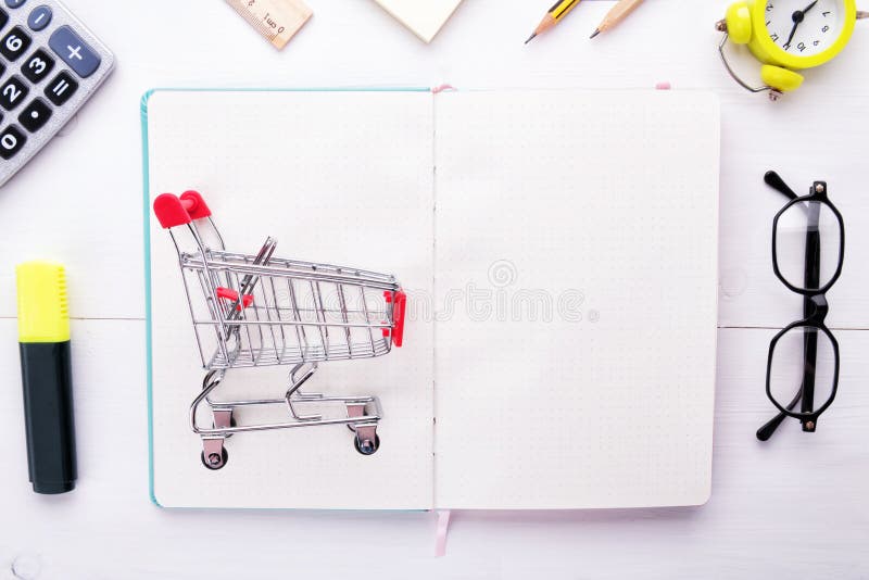 Organisieren Sie Ihre Einkaufsliste: kleine Lebensmittelgeschäftlaufkatze auf weißem sauberem Notizbuch oder Planer mit Briefpapi lizenzfreie stockfotos Organisieren Sie Ihre Einkaufsliste: kleine Lebensmittelgeschäftlaufkatze auf weißem sauberem Notizbuch oder Planer mit Briefpapi lizenzfreie stockfotos