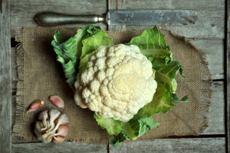 Organic cauliflower and garlic on a vintage background . bio food. vegan, green food . Eat a leafy, simple alkalin diet concept. Organic cauliflower and garlic on a vintage background . bio food. vegan, green food . Eat a leafy, simple alkalin diet concept