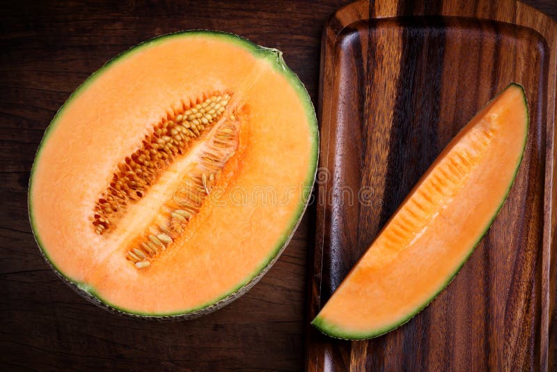 Organisk cantaloupmelon med redskap på trätabellen royaltyfria bilder Organisk cantaloupmelon med redskap på trätabellen royaltyfria bilder