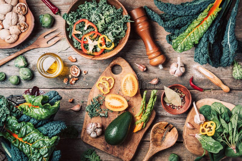Orgnic healthy vegan food cooking ingredients. Top view. Copy space. Green vegetables, seeds, avocado, nuts, kale, spices, salt