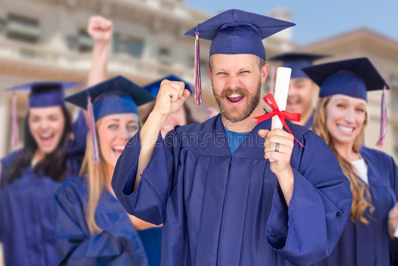 Orgulloso graduado masculino en Cap and Gown frente a otros graduados foto de archivo libre de regalías Orgulloso graduado masculino en Cap and Gown frente a otros graduados foto de archivo libre de regalías