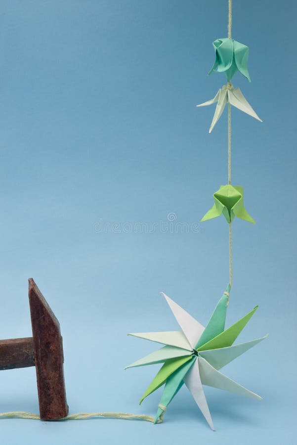 Star shaped paper origami on thread nailed by rusty hammer against blue background. Decagon stock images, royalty-free photos and pictures
