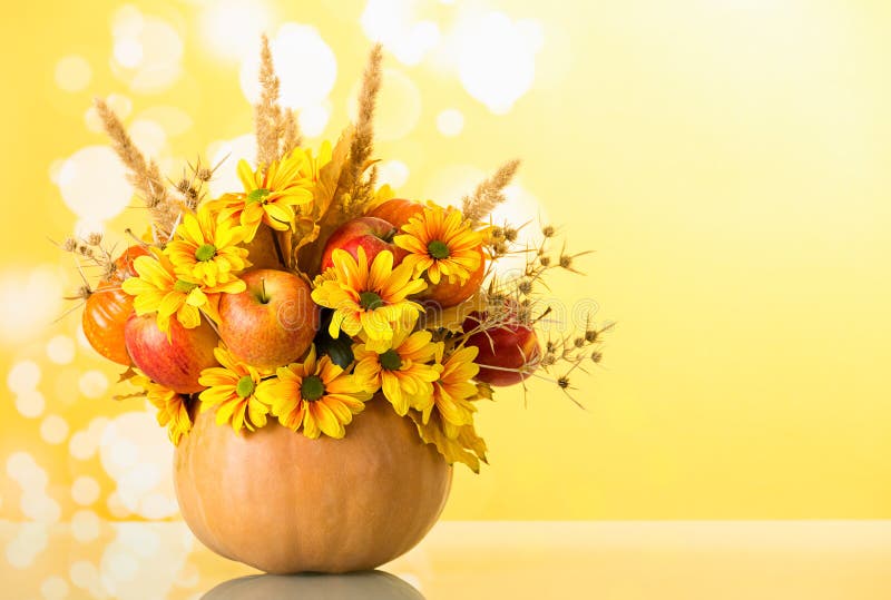 Original bouquet of fruits and flowers in vase of pumpkin, on light yellow