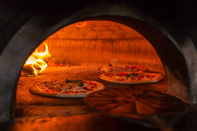 Original neapolitan pizza margherita in a traditional wood oven in Naples restaurant, Italy. Original neapolitan pizza margherita in a traditional wood oven in Naples restaurant, Italy