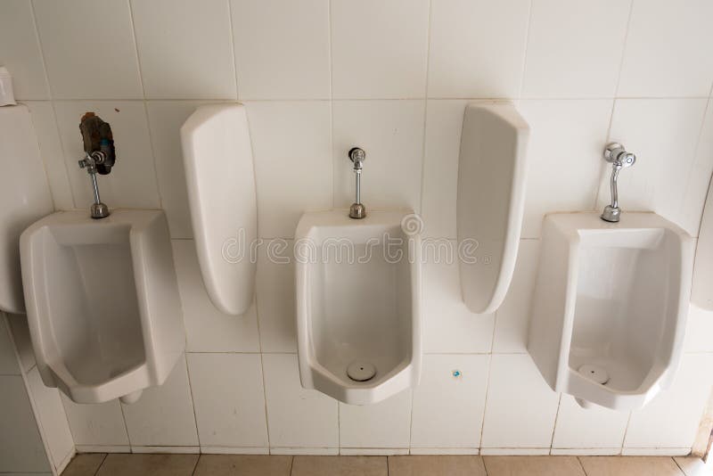 Orinali bianchi della porcellana nelle tolette pubbliche immagine stock Orinali bianchi della porcellana nelle tolette pubbliche immagine stock