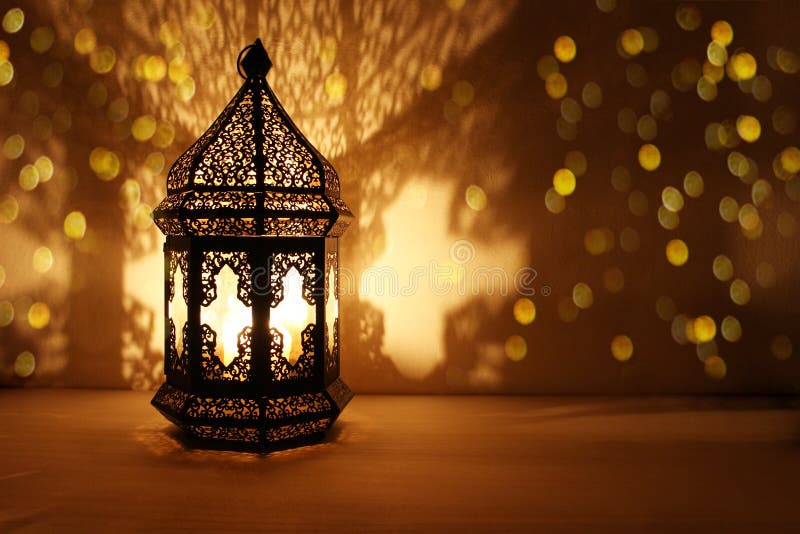Ornamentacyjny Arabski lampion z płonącą świeczką jarzy się przy nocą i błyskotliwymi złotymi bokeh światłami Świąteczny kartka z