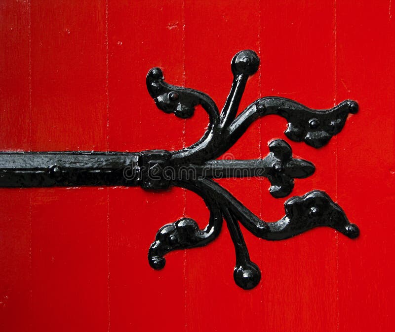 A Black Ornamental Hinge On Freshly Painted Red Door