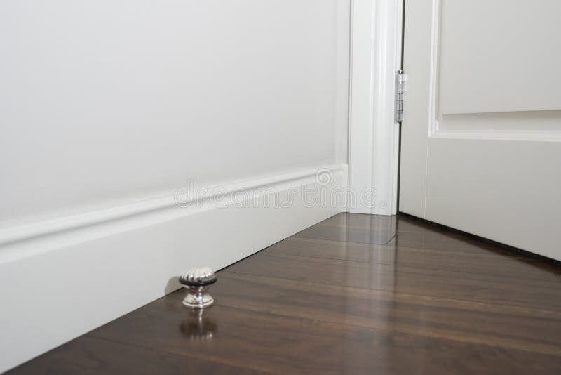 Ornamental moulding in the corner of a white room with dark wood floor interior concept. Beautiful internal view