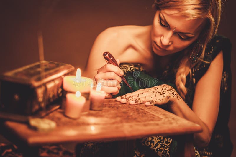 Woman drawing f henna menhdi ornament on her hand. Woman drawing f henna menhdi ornament on her hand