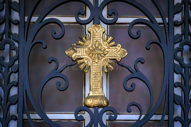 Ornate golden cross on decorative gate with intricate design stock images
