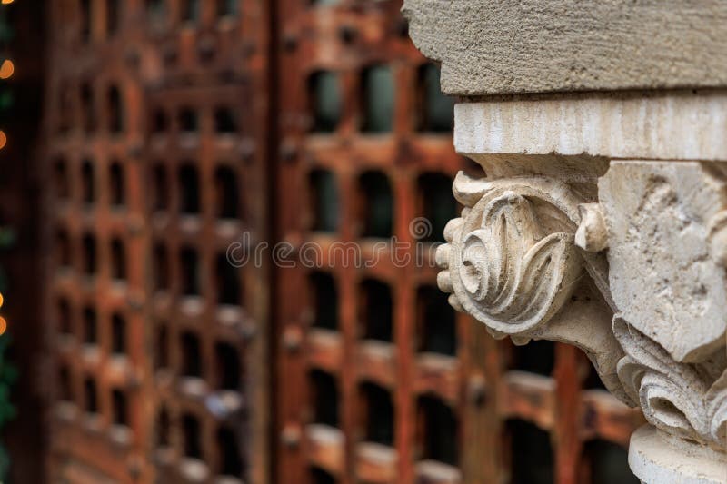 Ornate stone carving with historic wooden gate in background stock image
