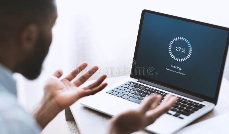 Slow computer software concept. Indignant african american guy looking at laptop with loading screen. Over shoulder shot, selective focus on device. Slow computer software concept. Indignant african american guy looking at laptop with loading screen. Over shoulder shot, selective focus on device