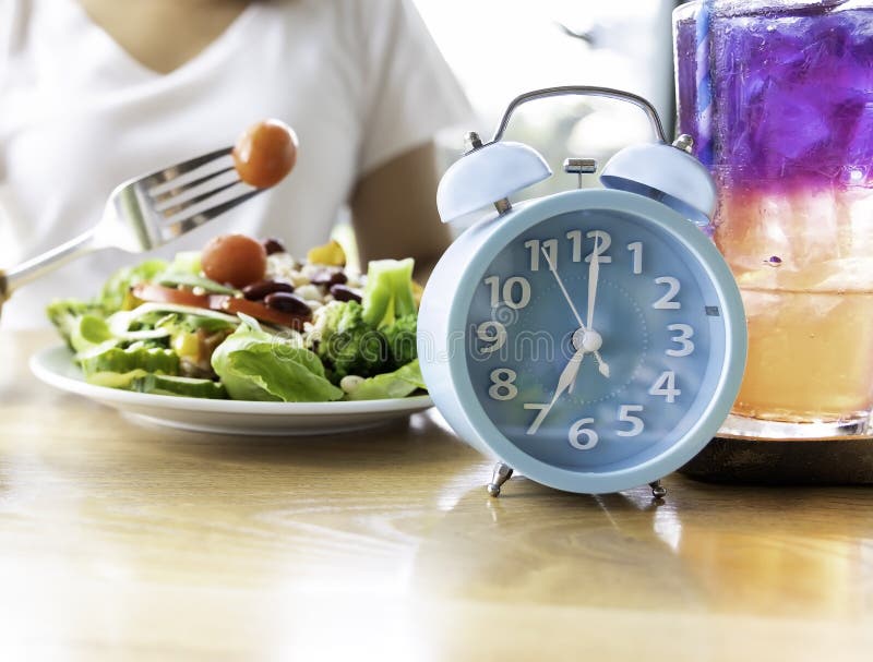 orologio blu che una donna fa un digiuno intermittente con un cibo sano di insalata Concetto di stile di vita sano