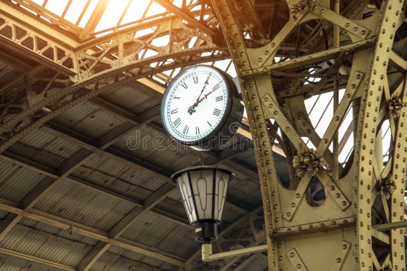 Orologio d'annata e lanterna sulla stazione ferroviaria con il tetto della costruzione