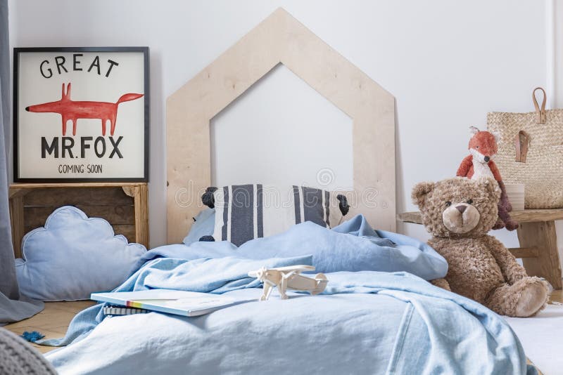 Orsacchiotto accanto al letto blu con gli strati nell'interno della camera da letto del bambino con il manifesto della volpe Foto