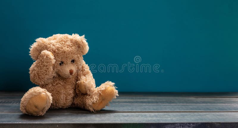 Orsacchiotto triste, sedendosi sul pavimento di legno, fondo vuoto blu della stanza, spazio della copia immagine stock Orsacchiotto triste, sedendosi sul pavimento di legno, fondo vuoto blu della stanza, spazio della copia immagine stock