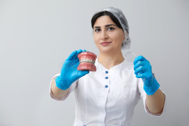 Orthodontist Showing Model of Human Jaw with Wire Braces and Aligners