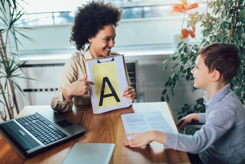 Orthophoniste pendant une session avec un petit gar?on photographie stock libre de droits Orthophoniste pendant une session avec un petit gar?on photographie stock libre de droits