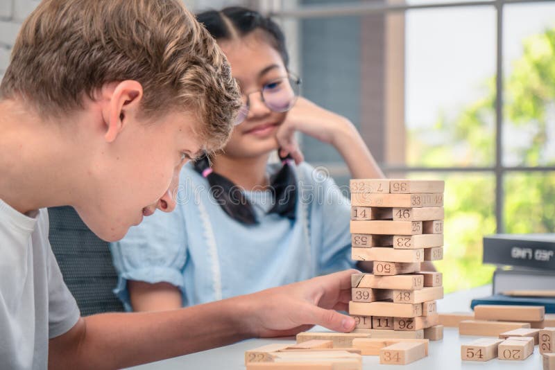 Os adolescentes jogam o jogo de Jenga junto fotos de stock Os adolescentes jogam o jogo de Jenga junto fotos de stock