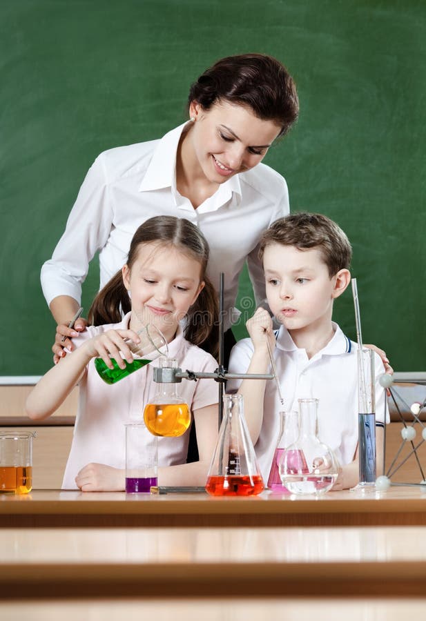 Little pupils study chemical liquids with their teacher. Little pupils study chemical liquids with their teacher