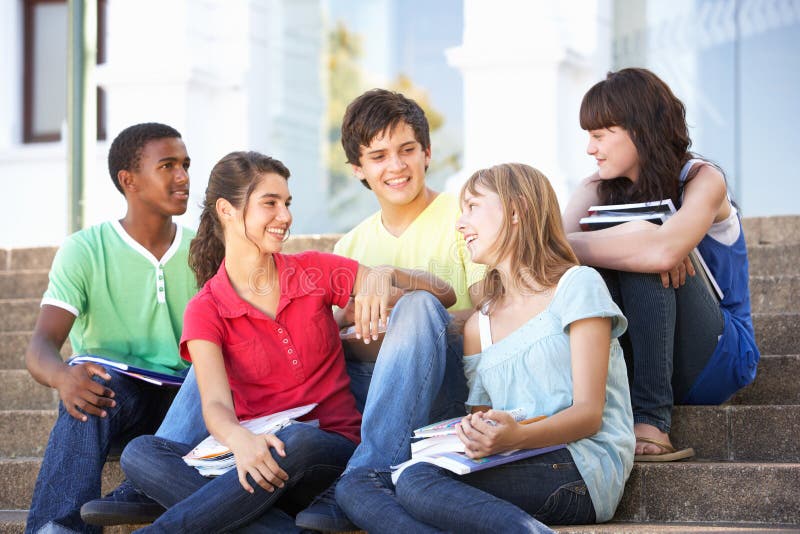 Os amigos adolescentes que sentam-se na faculdade pisam fora imagem de stock Os amigos adolescentes que sentam-se na faculdade pisam fora imagem de stock