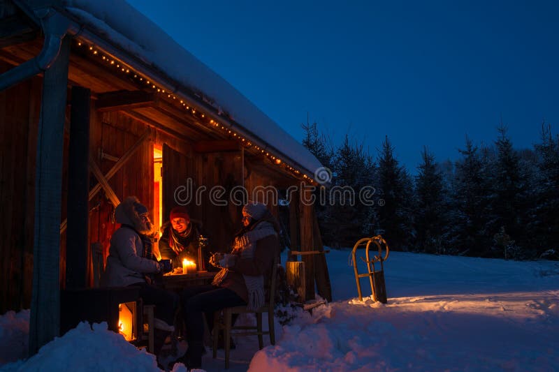 Os amigos da casa de campo do inverno da noite apreciam bebidas quentes
