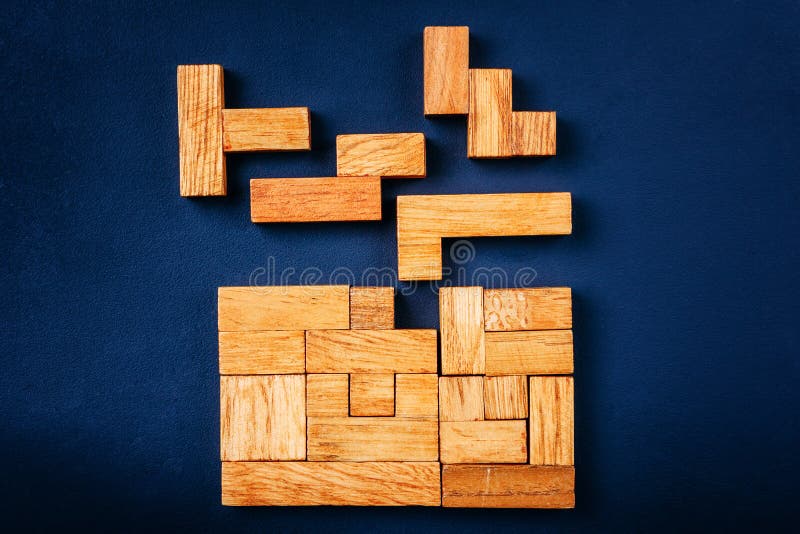 Os blocos de madeira das formas geométricas diferentes arranjam na figura contínua em um fundo escuro Conceito de resolução do pe
