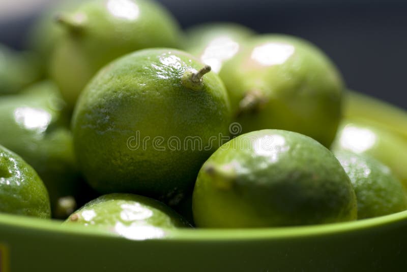 Limes up close in a green bowel in outdoor setting. Limes up close in a green bowel in outdoor setting.