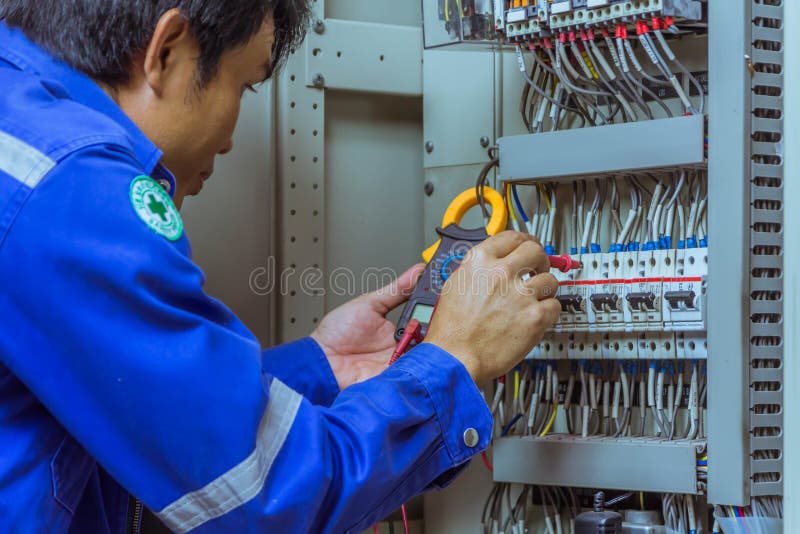 Os coordenadores masculinos estão verificando o sistema elétrico com as ferramentas eletrônicas, braçadeira-em, o grampo ampère, fotografia de stock royalty free Os coordenadores masculinos estão verificando o sistema elétrico com as ferramentas eletrônicas, braçadeira-em, o grampo ampère, fotografia de stock royalty free