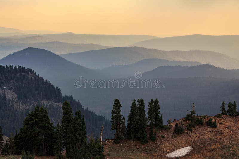 The ridges of the Cascade mountains viewed across the valley subtly fade in color from greenish blue to golden yellow as the sun sets. The ridges of the Cascade mountains viewed across the valley subtly fade in color from greenish blue to golden yellow as the sun sets